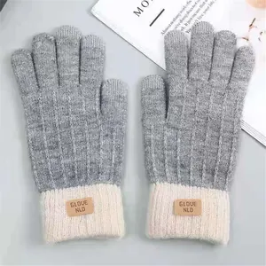 Detail view of grey and cream knitted warm winter gloves featuring GLOVE NLD leather patch
