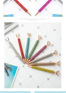 Close-up of colorful rhinestone ballpoint pens with large crystal diamond tops on grid background