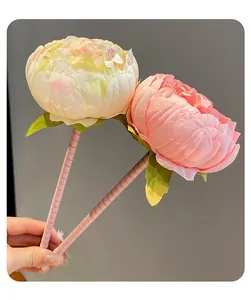 Close-up of pink and cream artificial peony flower pens with green leaves.