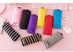 Variety of colorful monster zipper pencil cases displayed on a cute pink desk setup.