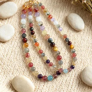 Detailed view of natural multi-color crystal gemstone beaded necklace on textured background.