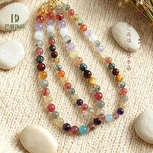 Detailed view of natural multi-color crystal gemstone beaded necklace on textured background.