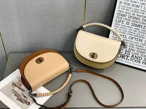 Detailed view of two elegant saddle bags in contrast colors with woven handle and metallic lock