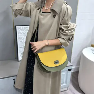 Detailed view of a stylish yellow and green color-block saddle bag with metal lock buckle