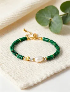 Detailed view of green bamboo-shaped beads and a freshwater pearl on an elegant bracelet.