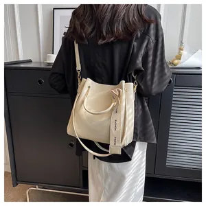 Close-up of a large beige textured bucket bag worn as a stylish shoulder bag on a model