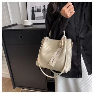 Close-up of a stylish cream-colored bucket bag with decorative strap detail