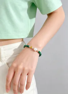 Detail shot of a natural green beaded bracelet with a large white pearl on a wrist