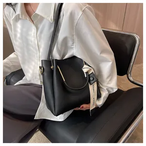 Elegant woman sitting with a black large-capacity leather bucket bag with ribbon detail