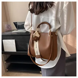 Close-up view of a modern brown leather bucket bag with decorative fashion ribbon.