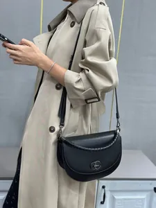 Elegant black saddle bag with silver hardware lock shown as a crossbody style