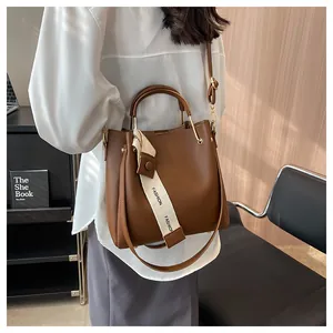 Close-up view of a stylish brown leather bucket bag being carried by a fashion model.