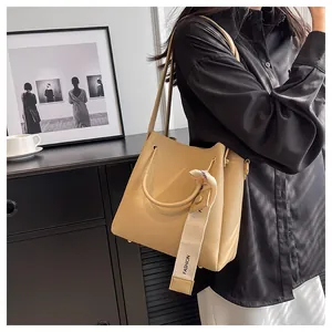 Close-up of a stylish beige leather bucket bag featuring a decorative strap detail