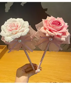 Handheld elegant rose-shaped ballpoint pens with pink lace ribbons and pearls.
