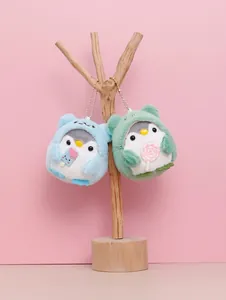 Close-up of two cute plush penguin keychains in hoodies hanging on a wooden stand