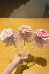 Nahaufnahme von drei eleganten Rosen-Kugelschreibern mit Seidenblüten und Schleifen