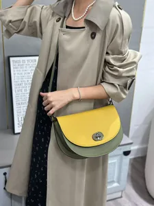 Fashionable color-block saddle bag featuring a yellow flap and olive green body with lock.