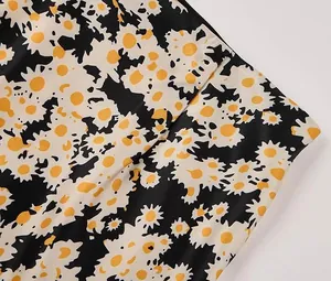 Close-up detail showing the daisy floral print and smooth texture of satin skirt fabric