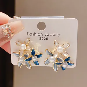 Detailed view of elegant flower earrings featuring faux pearls and blue enamel petals