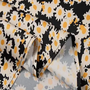 Detailed macro view of smooth satin fabric with yellow and white daisy floral print