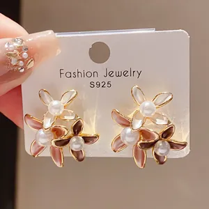 Detail view of flower earrings with faux pearls and enamel petals on 18K gold base