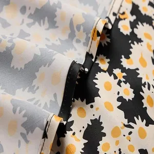 Detail shot of elegant satin skirt fabric with yellow and white daisy floral pattern