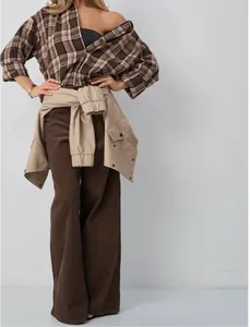 Detail view of retro brown plaid shirt styled with corduroy flare pants and waist-tied jacket.