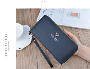 Close-up of a navy blue women's long wallet with a golden deer logo in hand