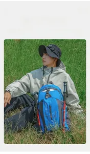 Young man resting with a blue 40L water-resistant hiking backpack in a grassy field