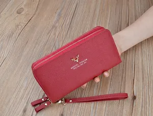 Dettaglio portafoglio lungo rosso da donna con doppia zip e logo dorato a testa di cervo.