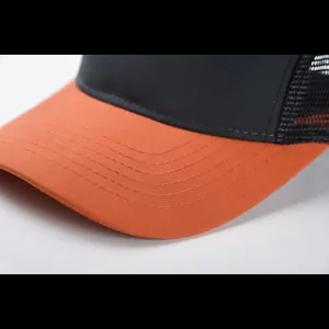 Dettaglio cappello trucker a 7 pannelli con visiera arancione e rete nera traspirante