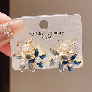 Detailed view of vintage flower earrings with blue petals and elegant faux pearl centers.