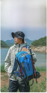 Model wearing a blue 40L water-resistant hiking backpack in a scenic lake landscape