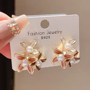 Close-up of 18K gold-plated flower earrings with pearls and pink enamel petals
