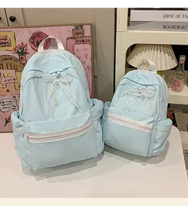 Pair of light blue student school backpacks featuring decorative lace and pearl bows