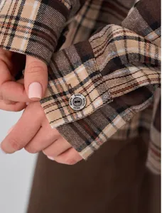 Close-up detail of a vintage plaid shirt cuff featuring an engraved metal button
