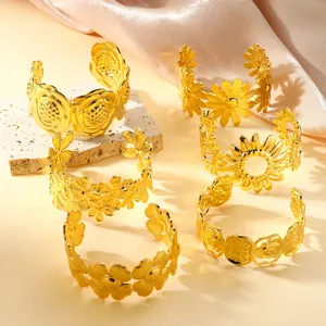 Detail view of various gold floral patterned titanium steel open cuff bracelets.