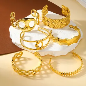 Detailed macro view of six minimalist gold stainless steel cuff bracelets with diverse textures
