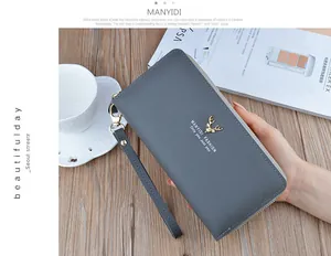 Detailed view of a stylish grey double zipper long wallet held in hand on a wooden desk