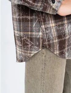 Close-up of distressed plaid pattern and curved hem on vintage brown flannel shirt