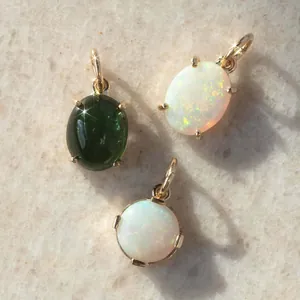 Detailed macro view of natural oval and round opal pendants in elegant gold settings