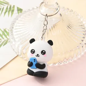 Detailed view of a cute cartoon panda keychain holding a blue phone with metal ring.