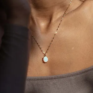 Elegant oval white opal pendant necklace with a shimmering gold chain on a model