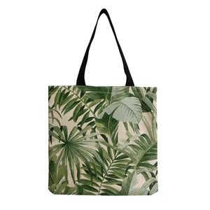 Close-up detail showing the vibrant tropical green leaf print on a canvas tote bag.