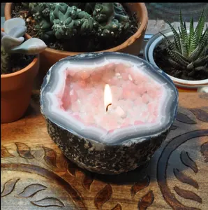 Detail view of a creative geode-style pink crystal candle bowl lit on a wooden table.