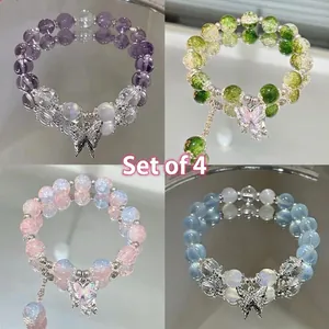 Close-up of butterfly charms on multi-colored beaded bracelets in purple and green hues.