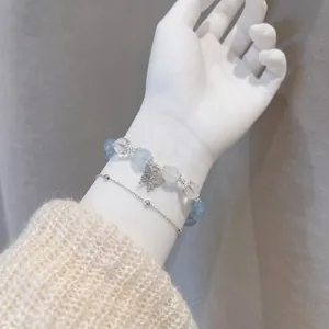 Close-up of elegant beaded butterfly bracelet and silver chain on wrist