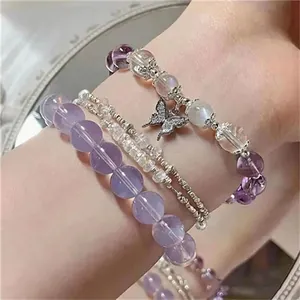 Close-up of lavender purple and clear beaded bracelets with a butterfly charm on wrist.