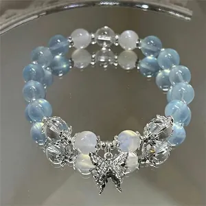 Close-up of a blue and white beaded bracelet with a sparkling butterfly pendant.