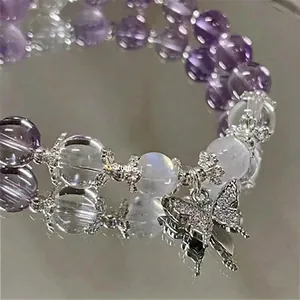 Macro view of an elegant purple beaded bracelet featuring a sparkling silver butterfly charm